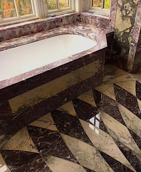 A bathroom with a bathtub and a marble floor.