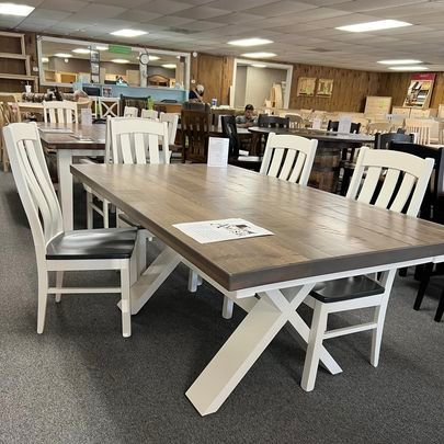 A wooden table with white chairs in a store.