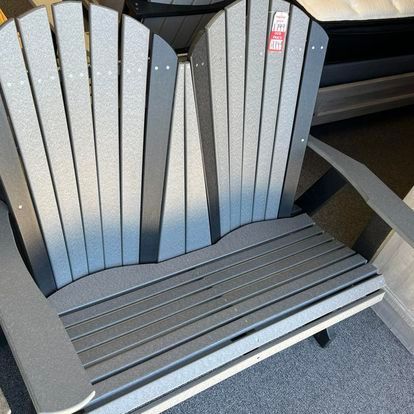 A gray adirondack chair is sitting on a carpet next to a mattress.