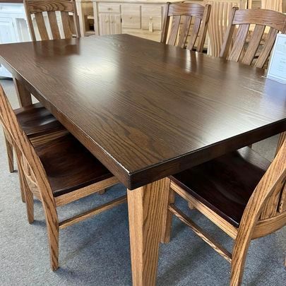 A wooden dining table and chairs are sitting on top of a carpeted floor.