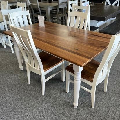 A wooden table with white chairs in a room.