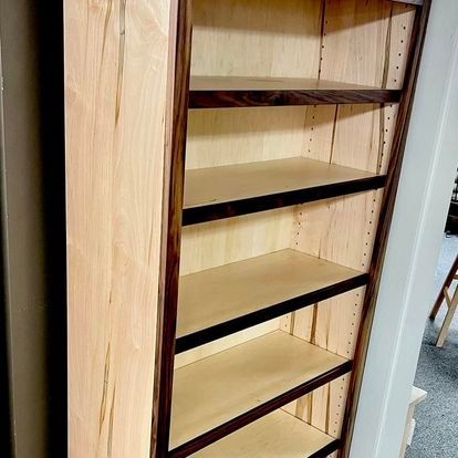 A wooden bookshelf with four shelves is sitting in a room.