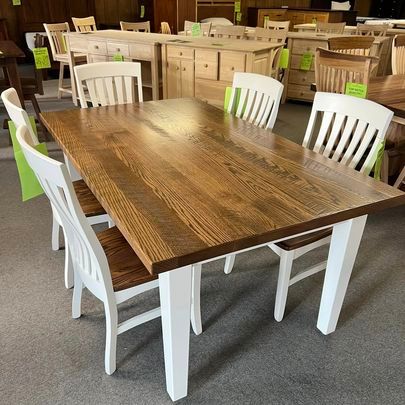 A wooden dining table with white chairs in a store.