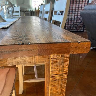 A wooden dining table with white chairs in a living room.