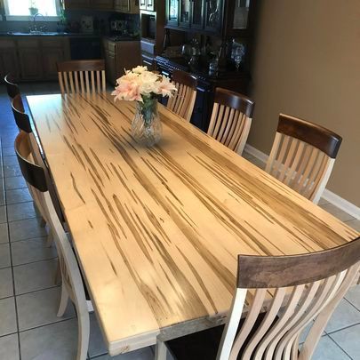 A wooden dining table with chairs and a vase of flowers on it.