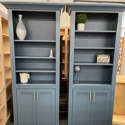 A pair of blue bookcases with shelves and cabinets in a room.