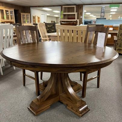 A round wooden table with four chairs in a room.