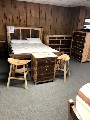 A bedroom with a bed , dresser , nightstand , and stools.