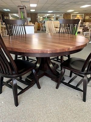 A wooden dining table with four chairs in a room.