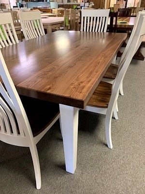 A wooden dining table with white chairs in a room.