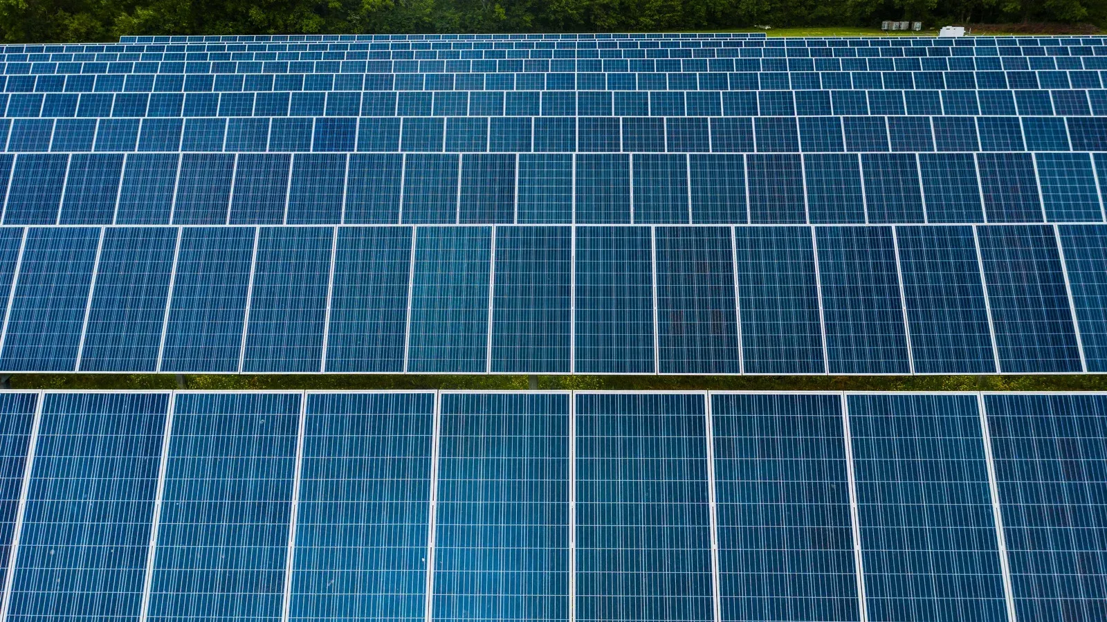 Aerial view of solar panels, rows of blue rectangles capturing sunlight.