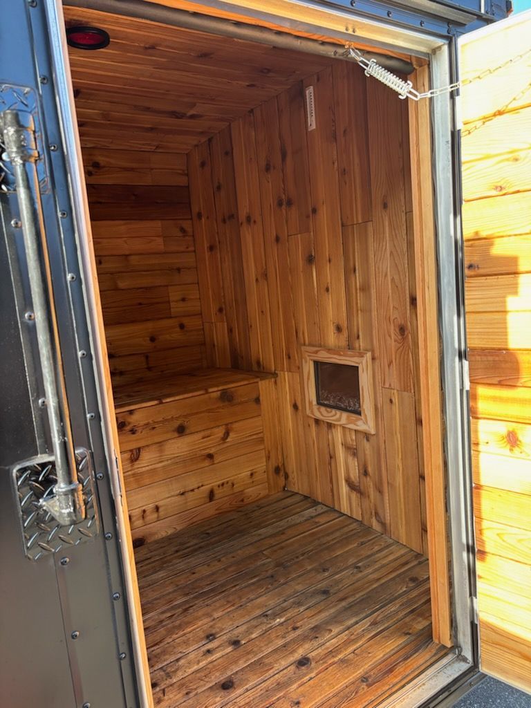 Interior of a small wooden sauna with a bench and a small window in the wall.