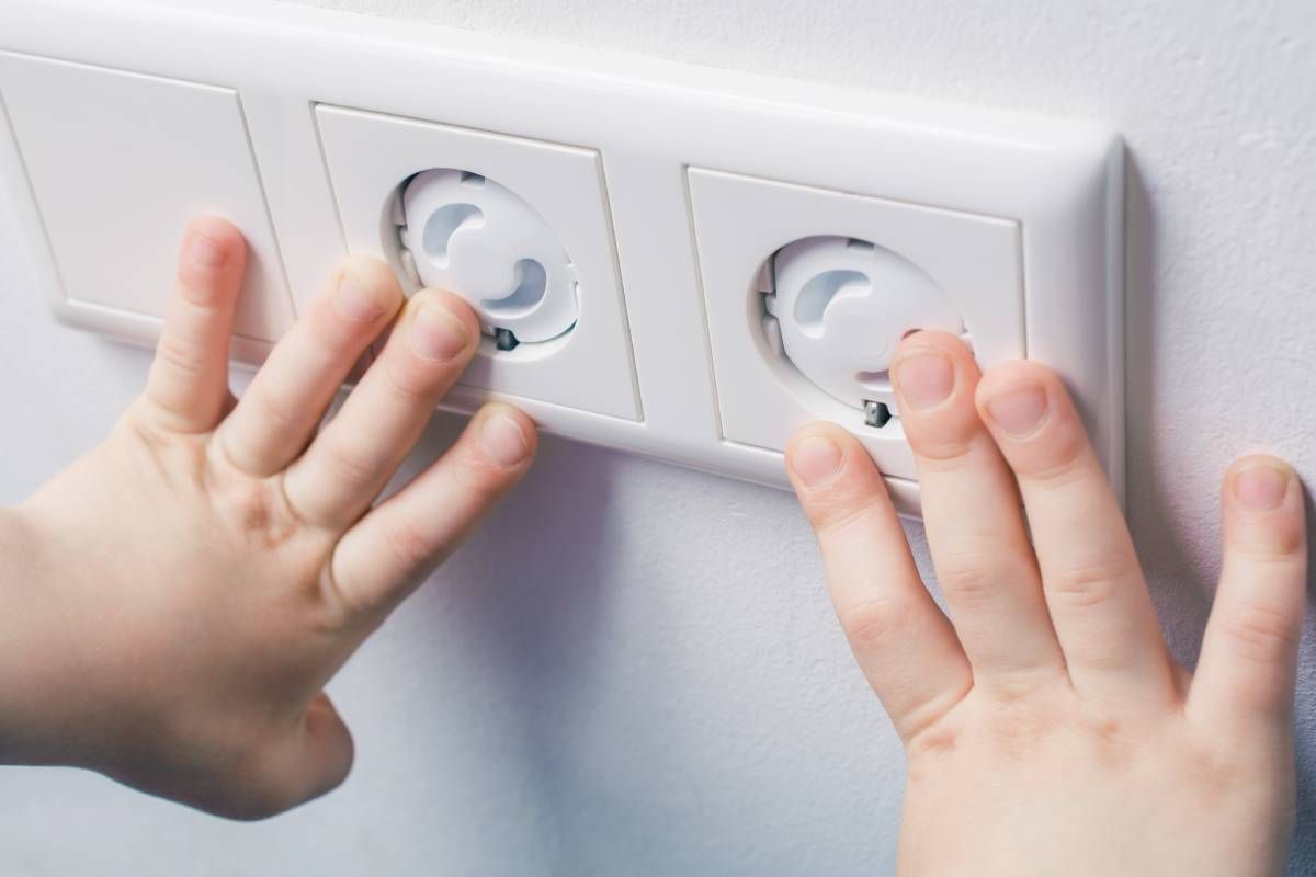 A pair of child's hands touching child-safe outlets in a safe and comfortable childcare facility at Walker Electric near Lexington, KY