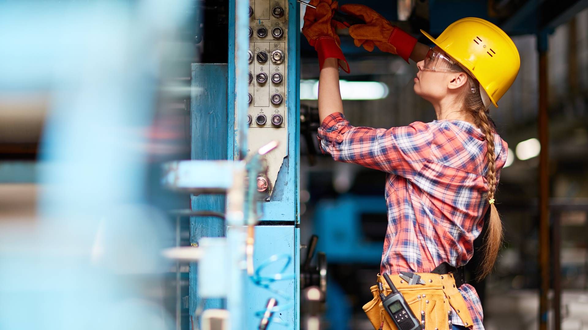 An electrician working on a job while wearing a yellow hard hat and red electrical gloves at Walker 