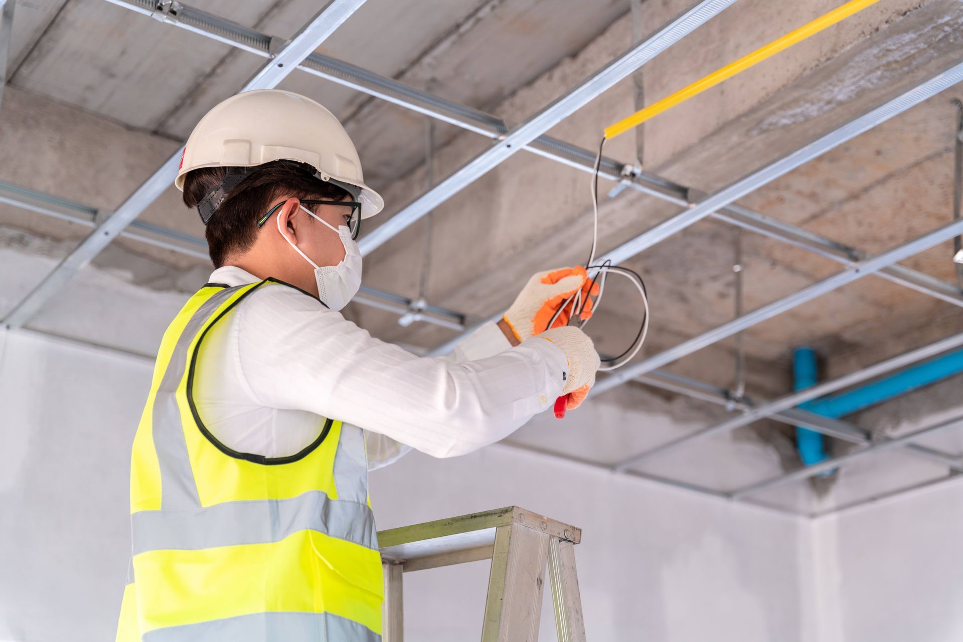 A professional electrician working on a light fixture repair in a commercial space
