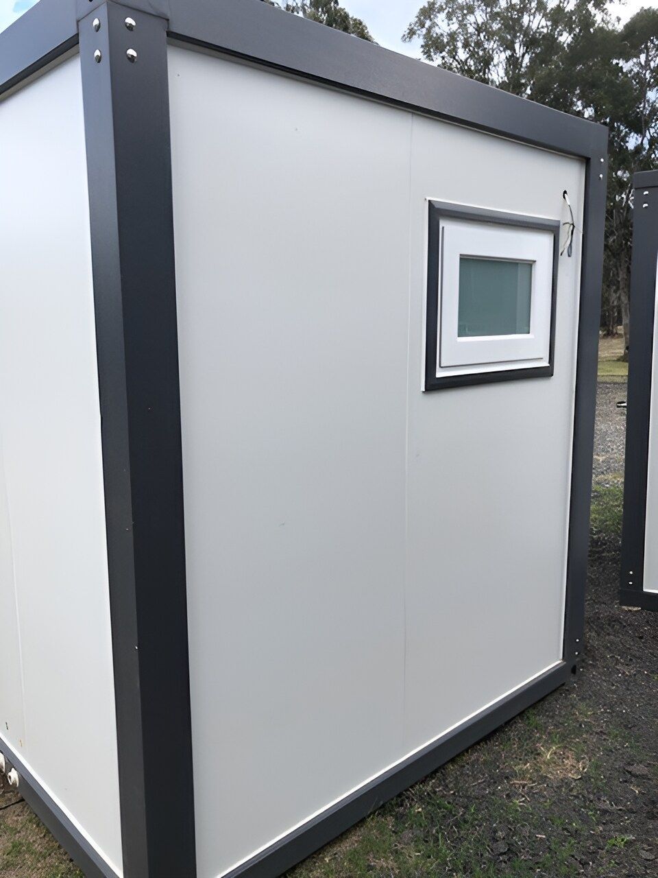 A Small White Building With A Window On The Side Is Sitting In The Grass — NQ Trading In Edmonton, QLD