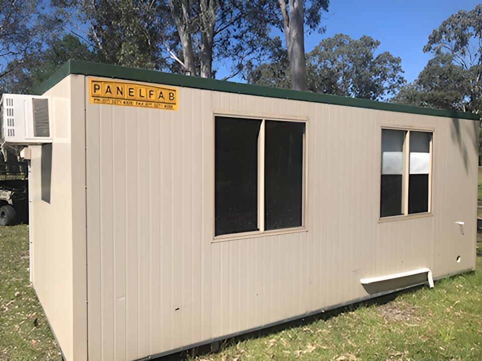 A Small Building With A Green Roof And A Yellow Sign That Says Panelfab — NQ Trading In Edmonton, QLD