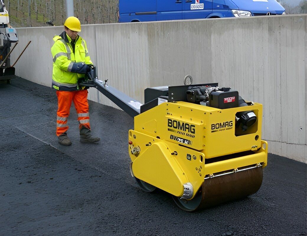 A Man Is Pushing A Yellow Bomag Roller — NQ Trading In Edmonton, QLD