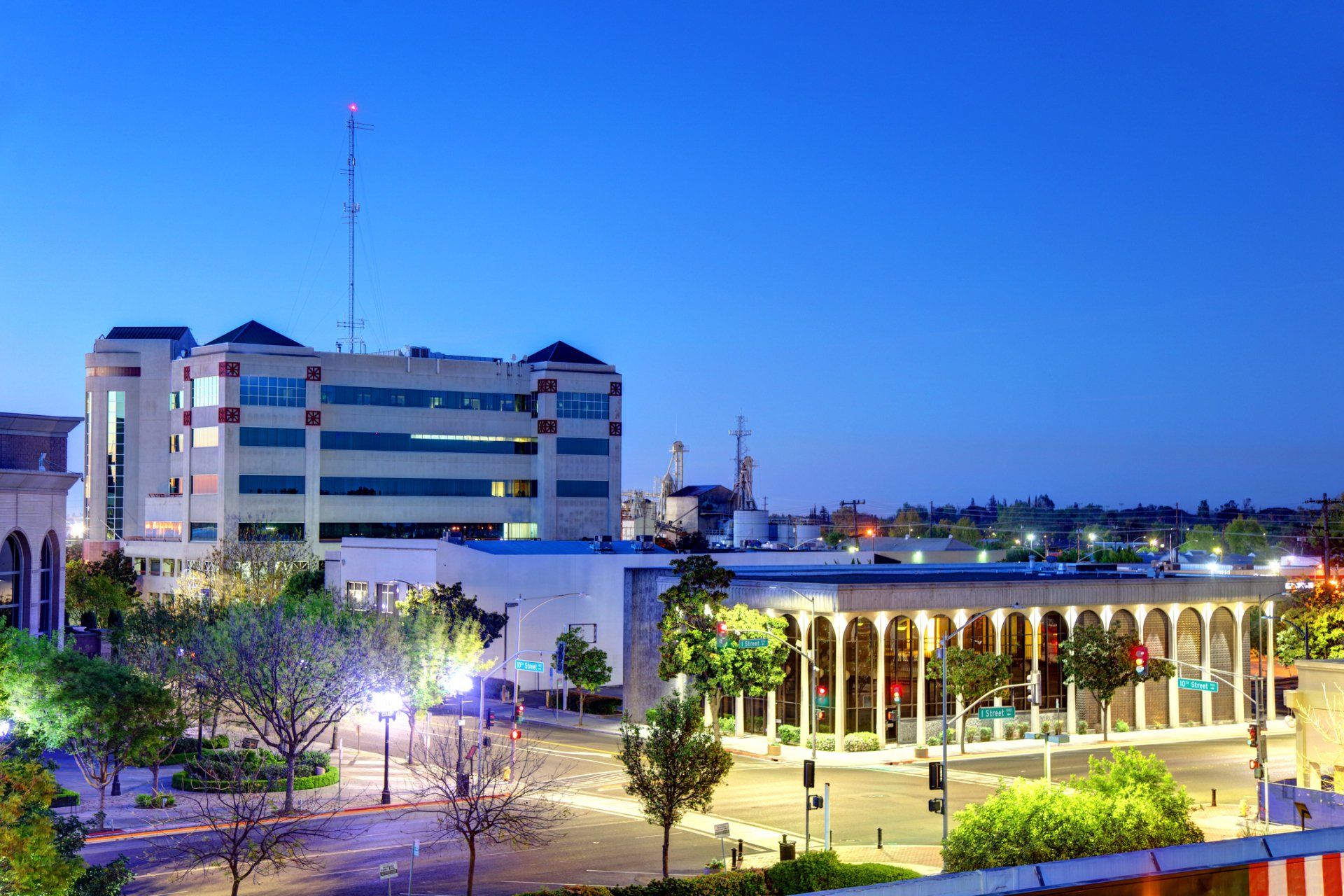 Evening view of downtown building with arched colonnade and multi-story building, under a dusky blue sky.