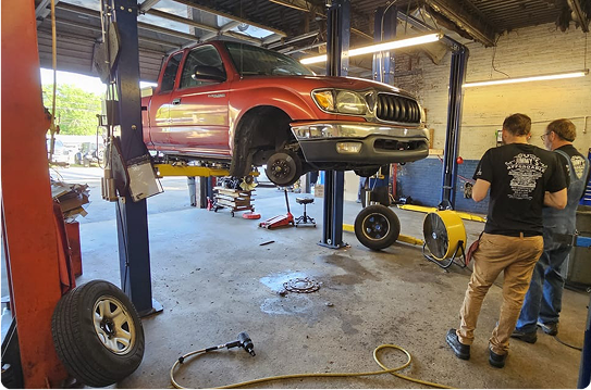 A red truck is sitting on a lift in a garage.