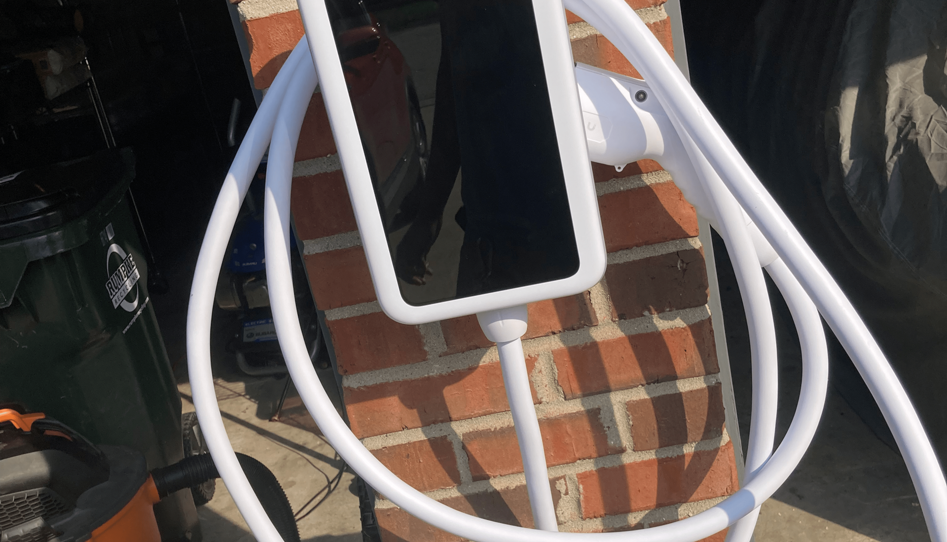 White EV charging cable with charger mounted on a brick wall.