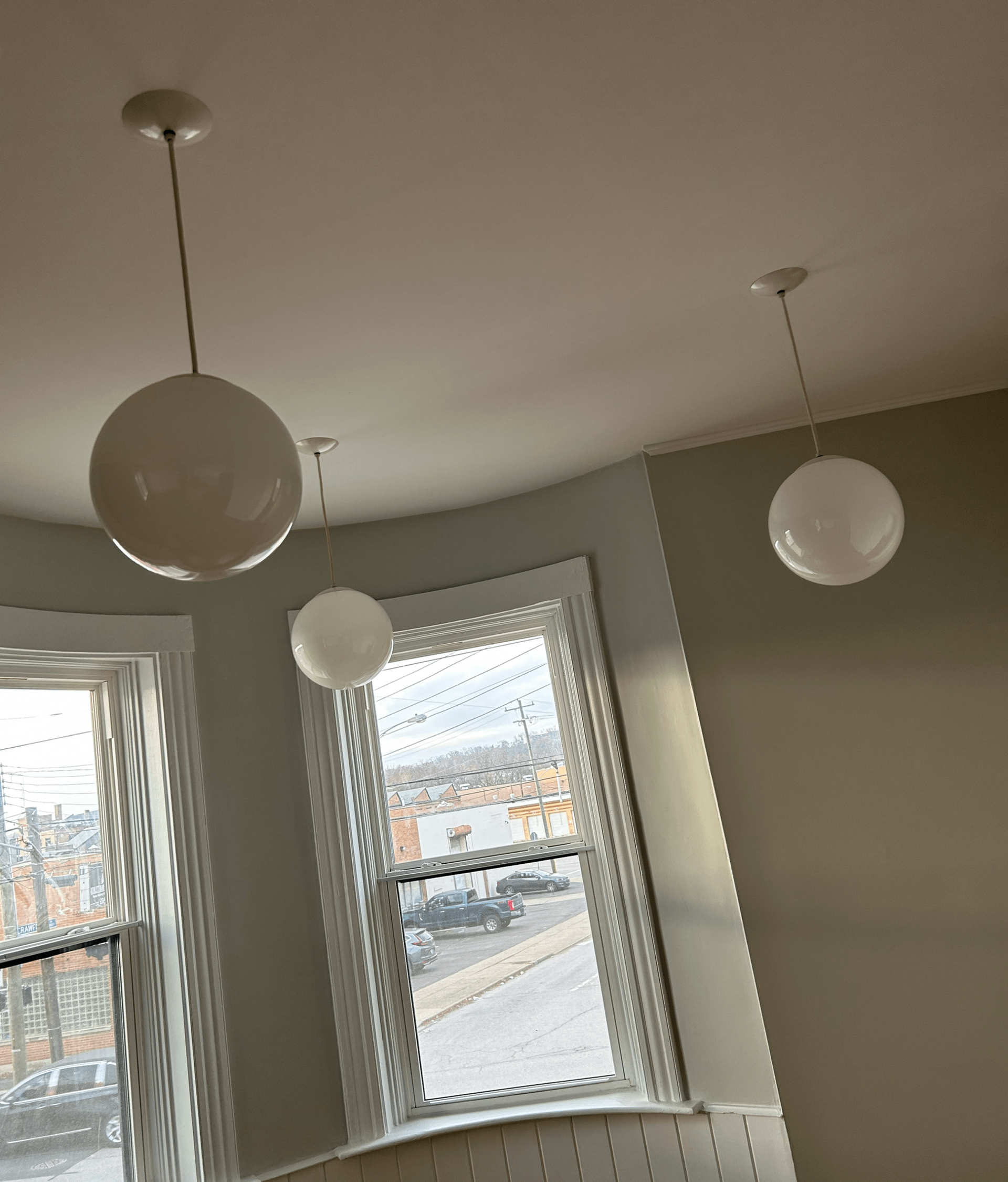Three white globe pendant lights hanging near a window.