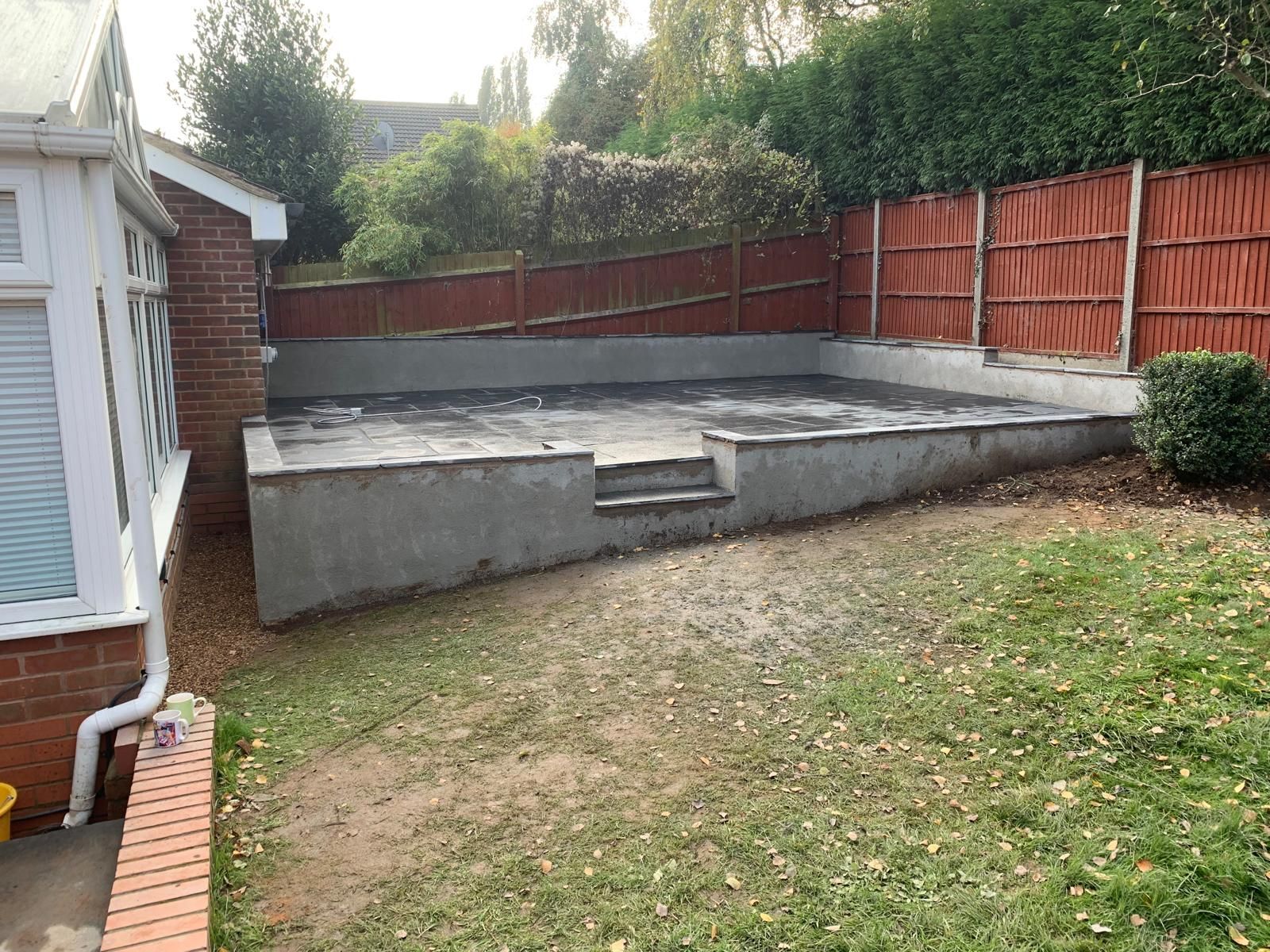 A backyard with a concrete wall and a red fence