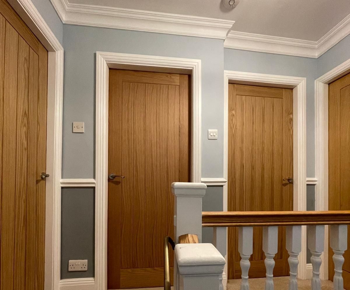 A hallway with wooden doors and a white railing