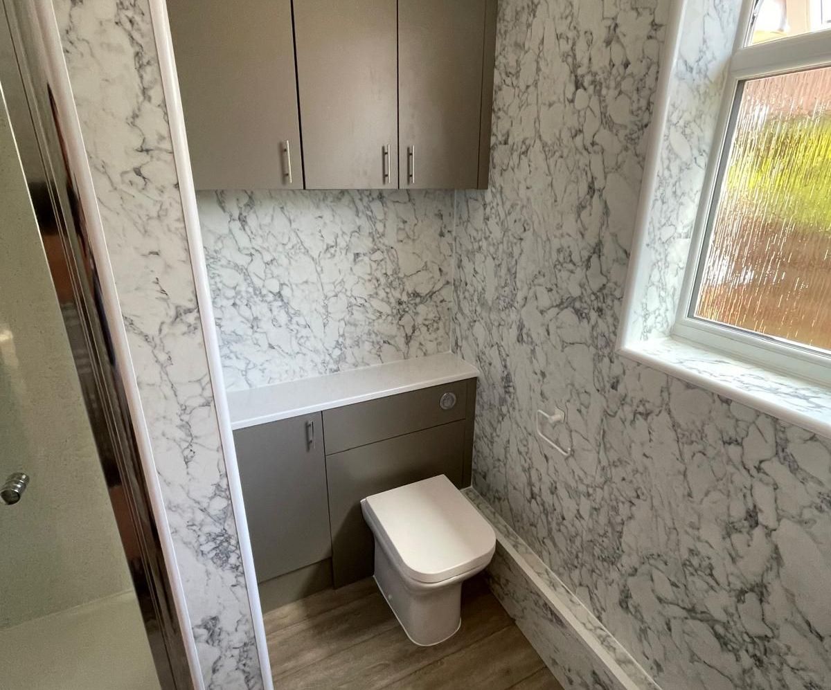 A bathroom with marble walls and a toilet.