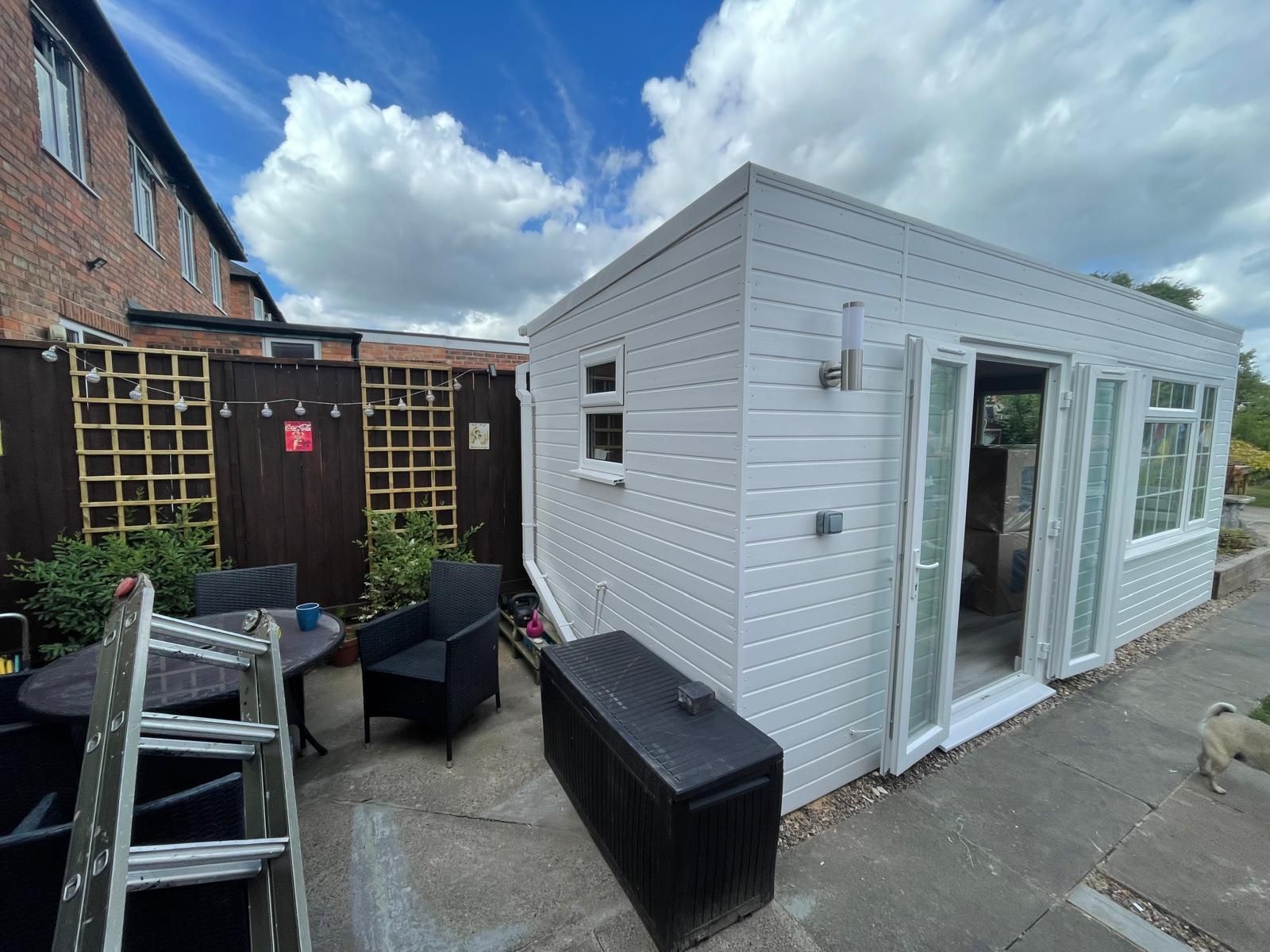 A white building with a table and chairs in front of it.
