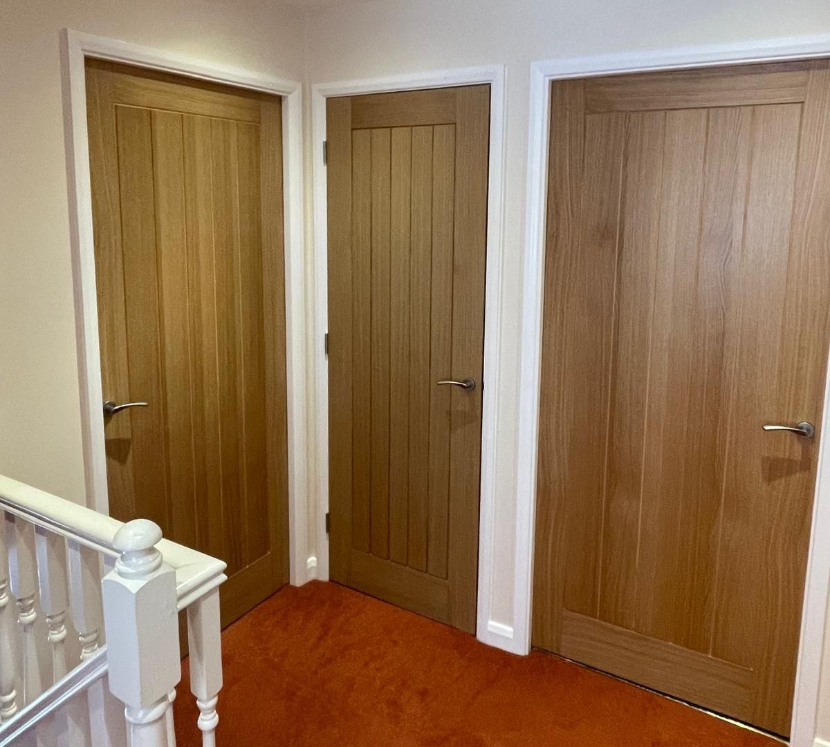 A hallway with wooden doors and a white railing