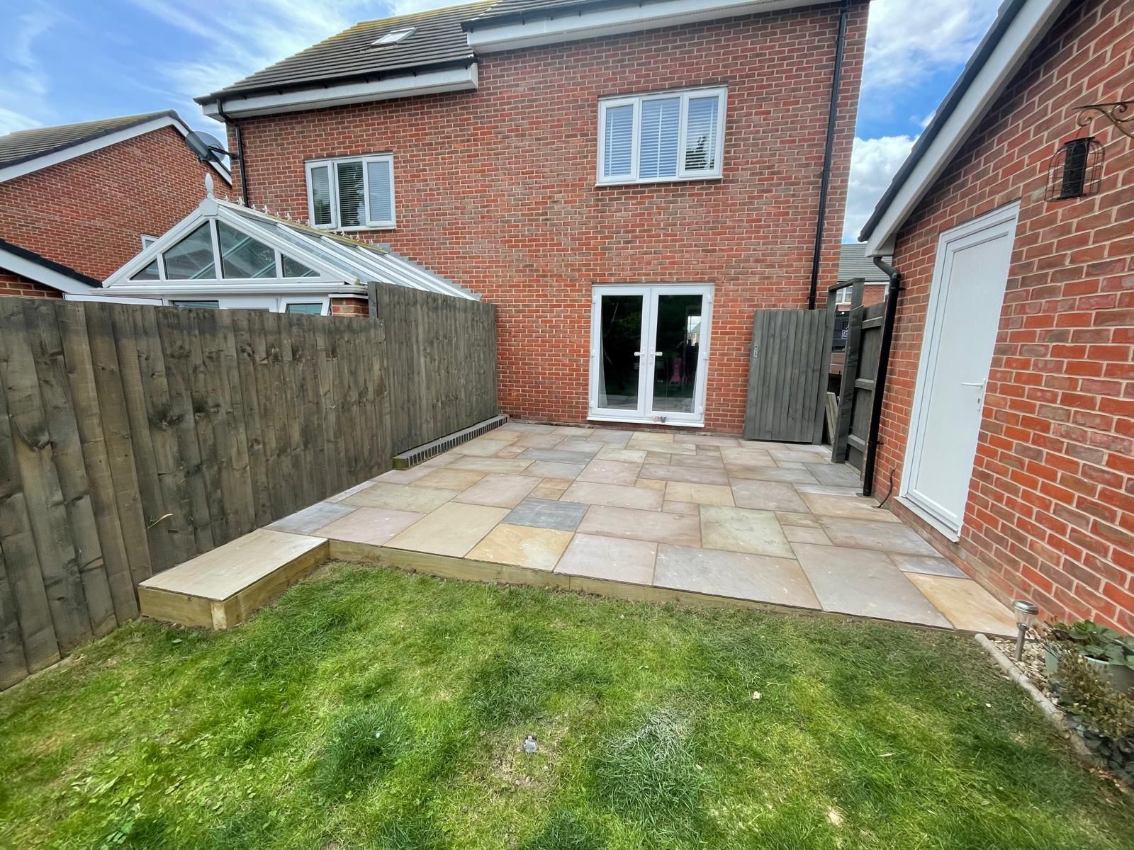 A brick house with a patio and a wooden fence in the backyard.