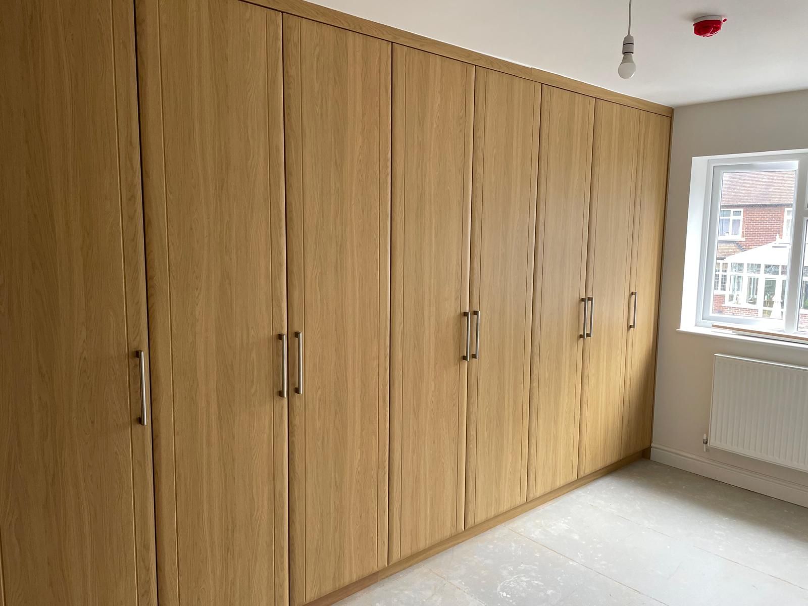 A room with a lot of wooden cabinets and a window.