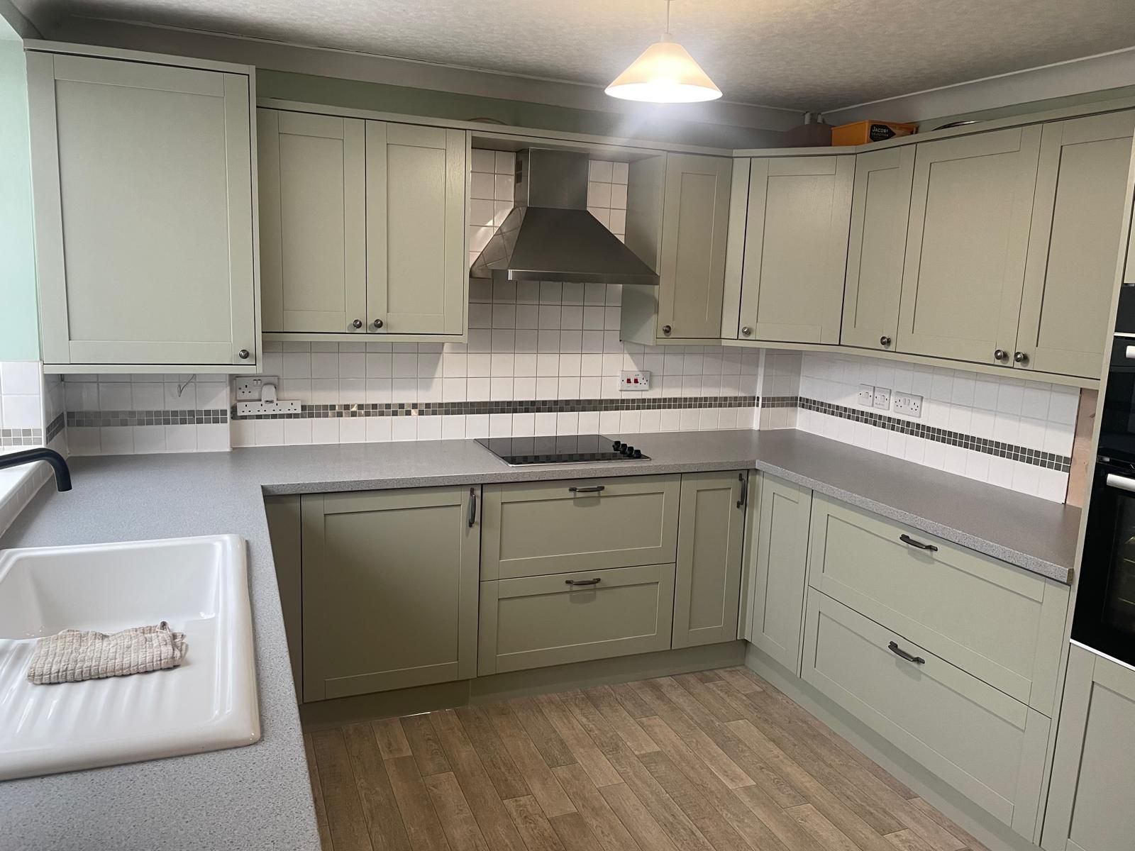 A kitchen with white cabinets , a sink , and a stove.