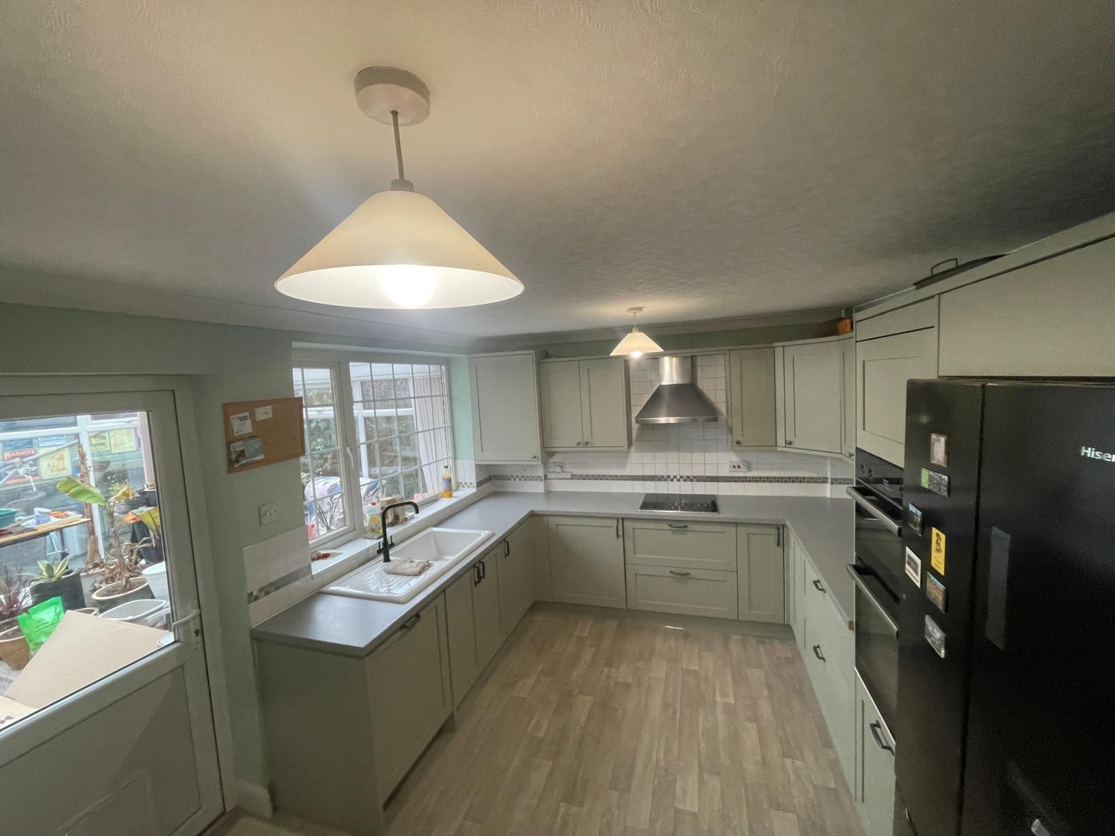 A kitchen with white cabinets and a black refrigerator.