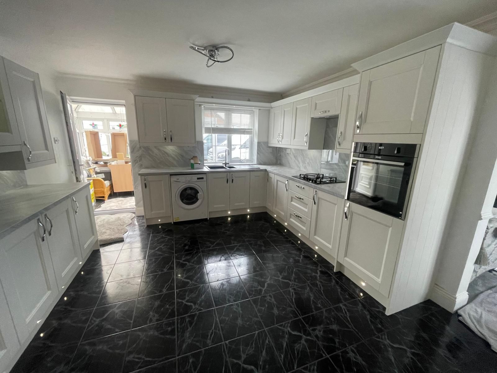 A kitchen with white cabinets and black tile floors.