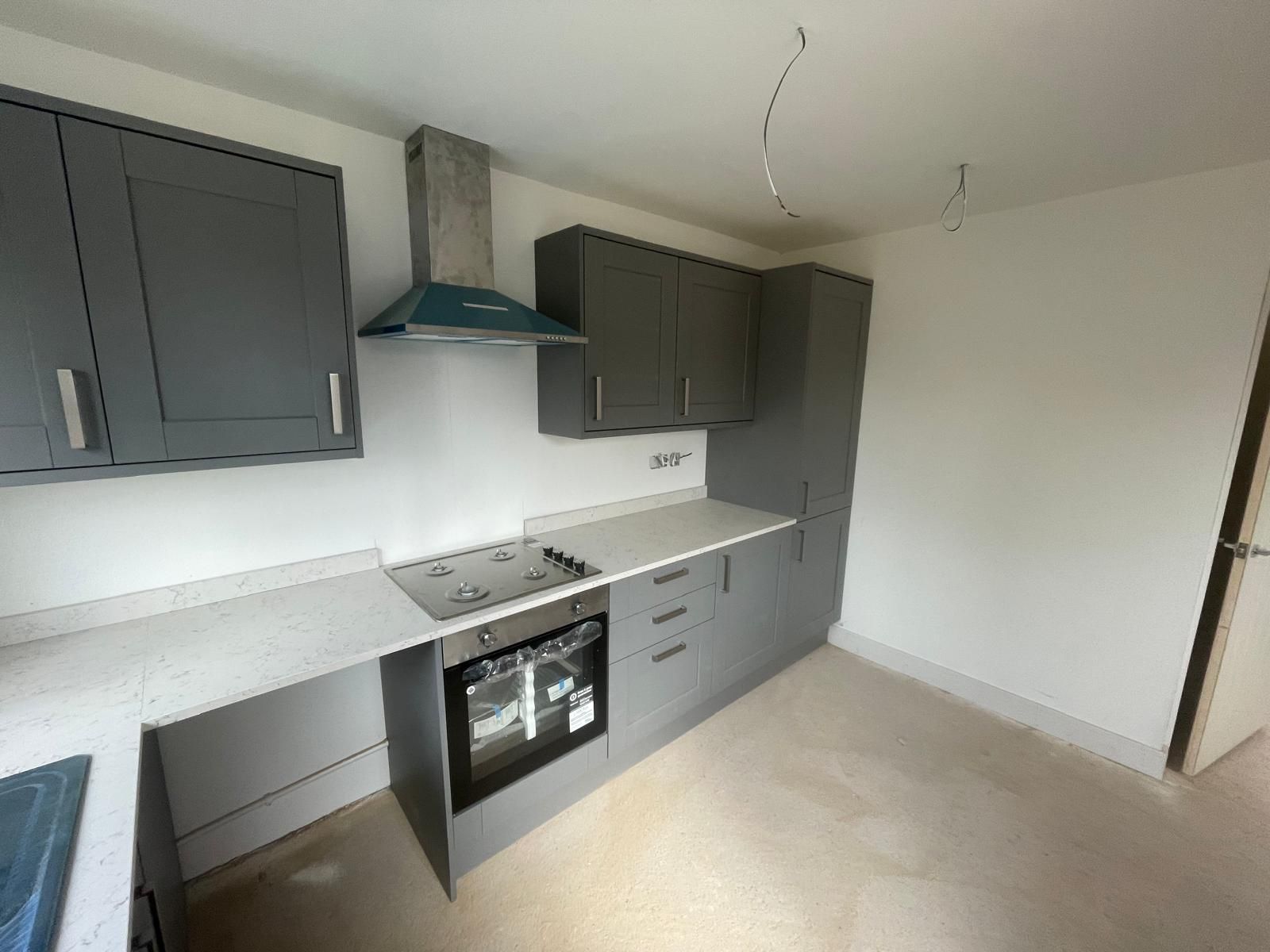 A kitchen with gray cabinets and a stove top oven