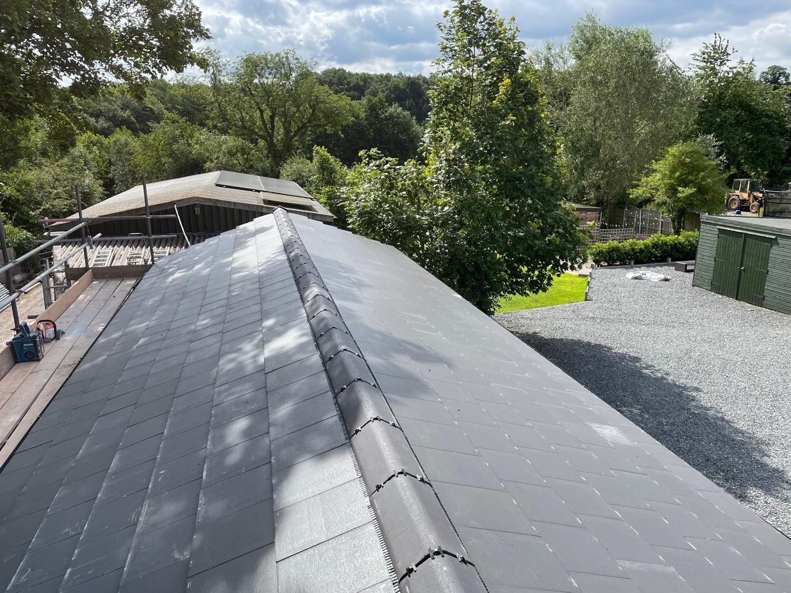 The roof of a house is being built and is surrounded by trees.