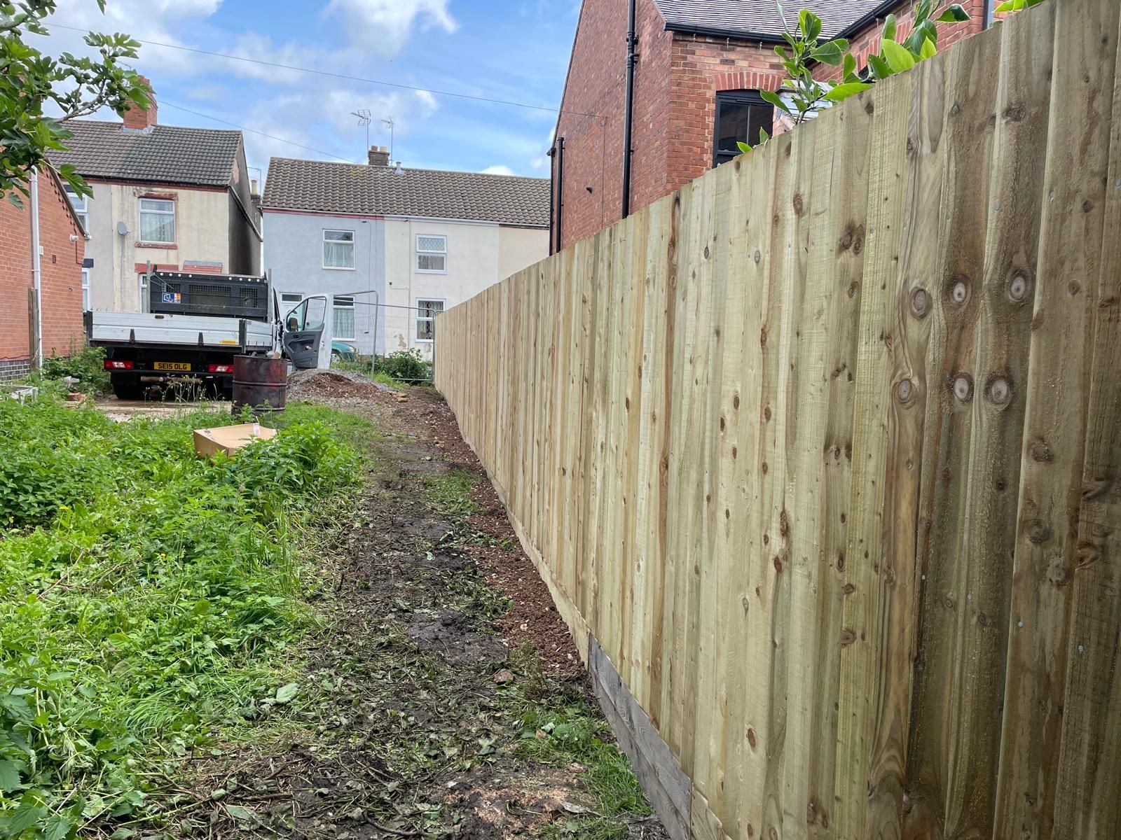 A wooden fence is surrounding a lush green field.