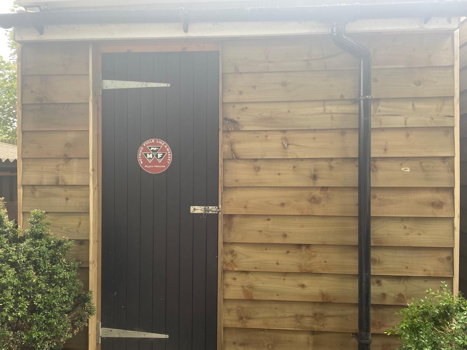 A wooden shed with a black door and a sign on it