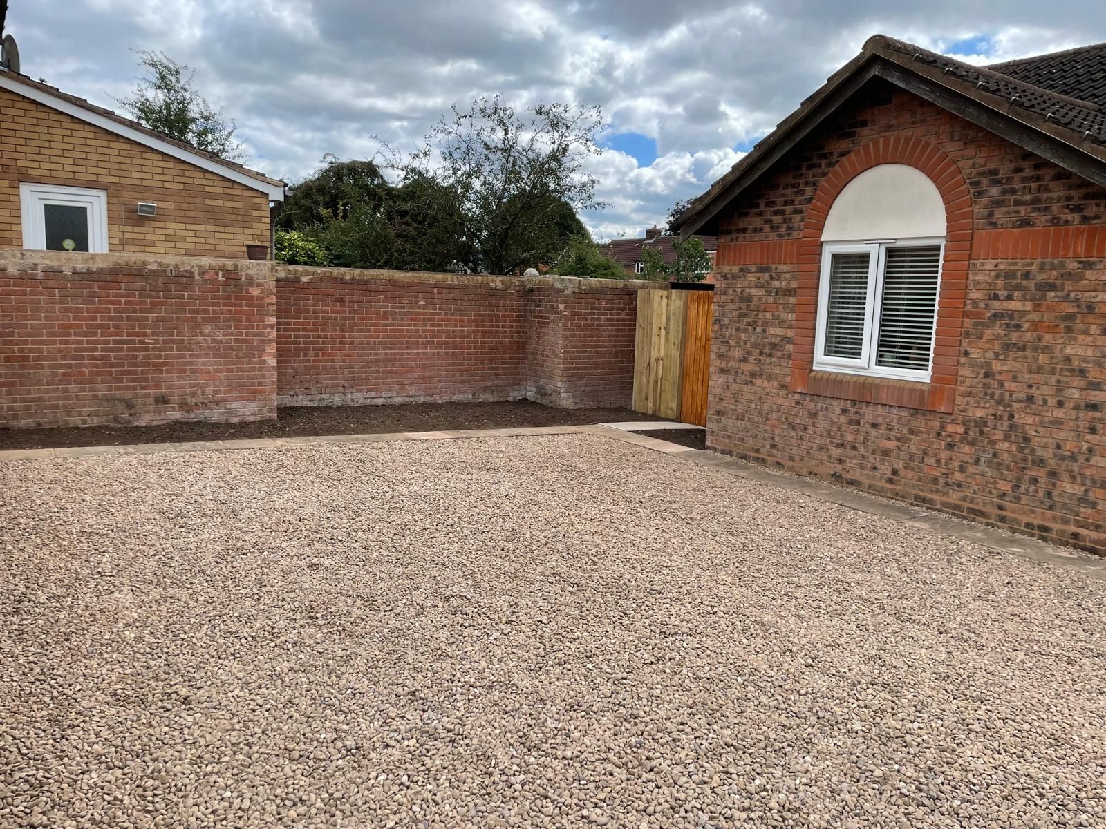 A brick building with a gravel driveway in front of it.