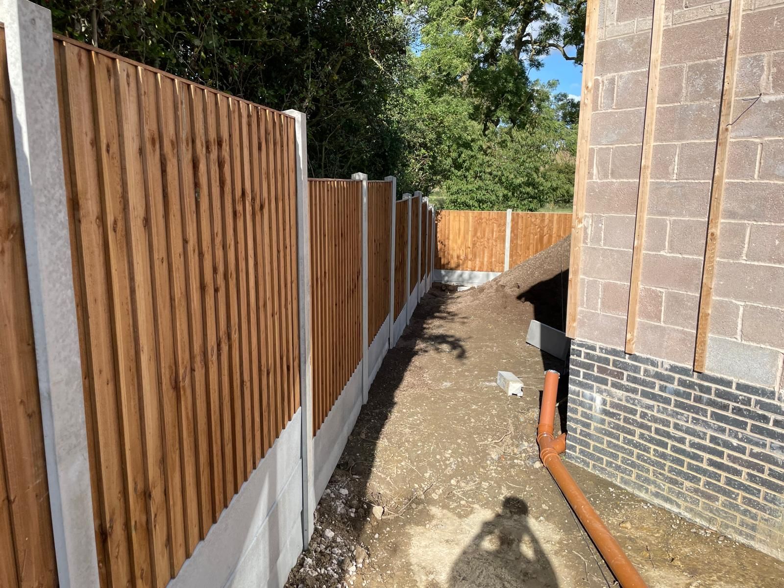 A wooden fence is surrounding a brick building.