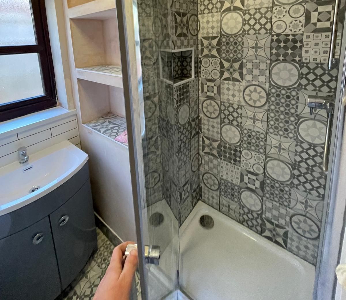 A person is standing in a bathroom with a shower and a sink.
