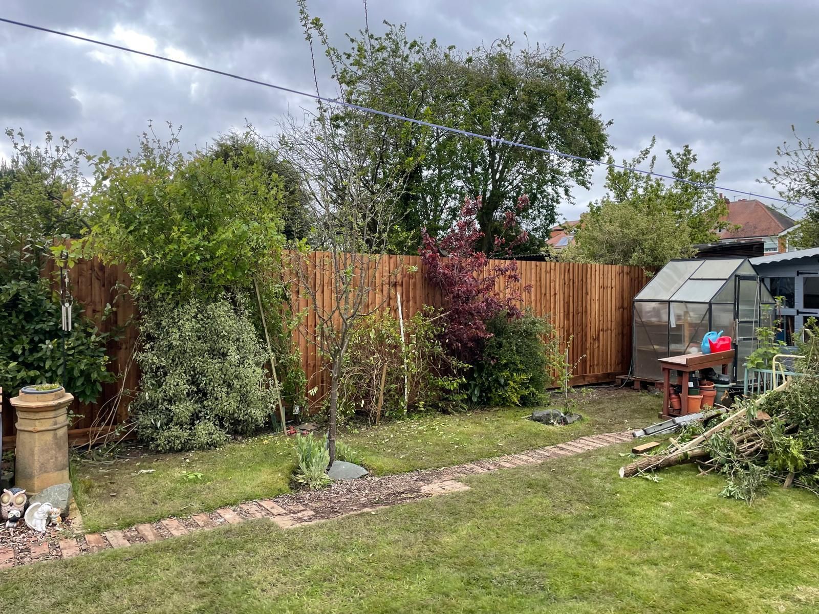 A backyard with a wooden fence and a greenhouse.