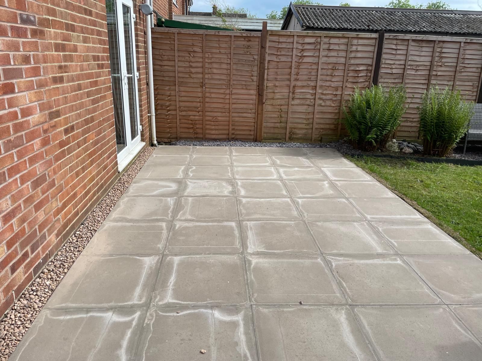 A patio with a wooden fence in the backyard of a house.