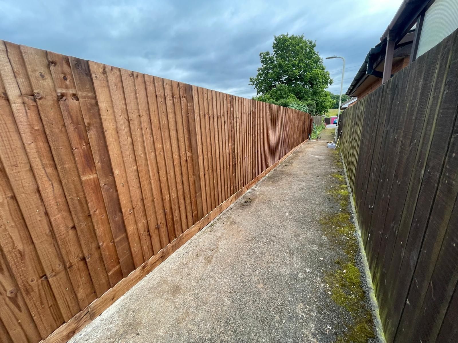 A wooden fence along a sidewalk next to a house.