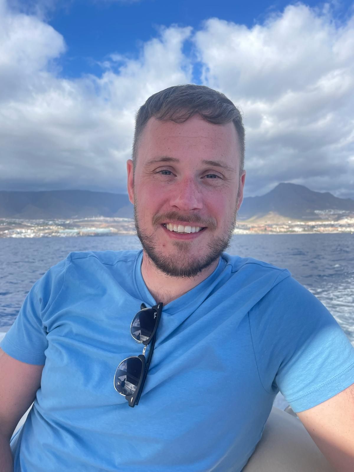 Bradley Williams in a blue shirt is sitting on a boat in the ocean.
