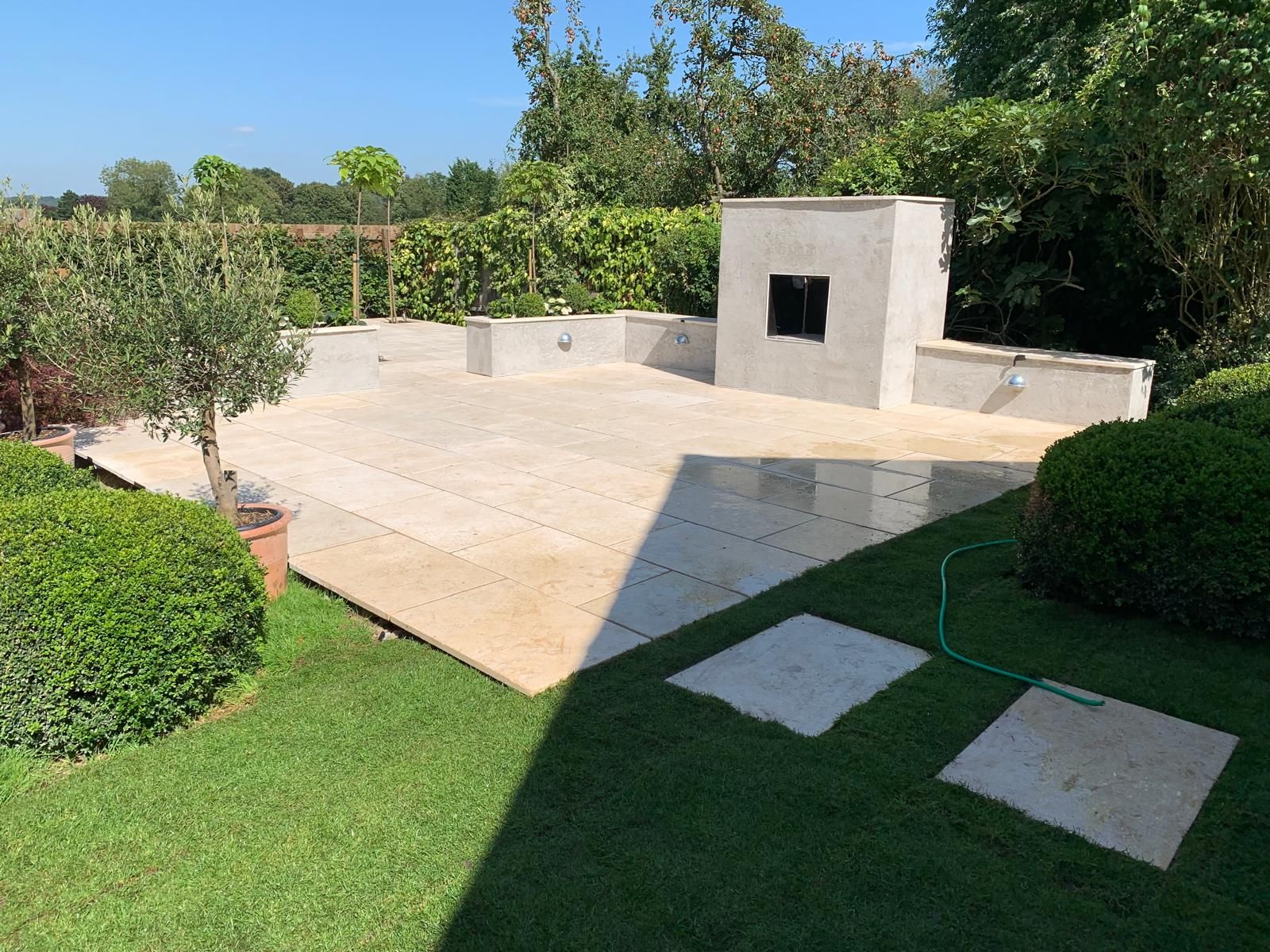 A lawn with a patio and a fireplace in the background