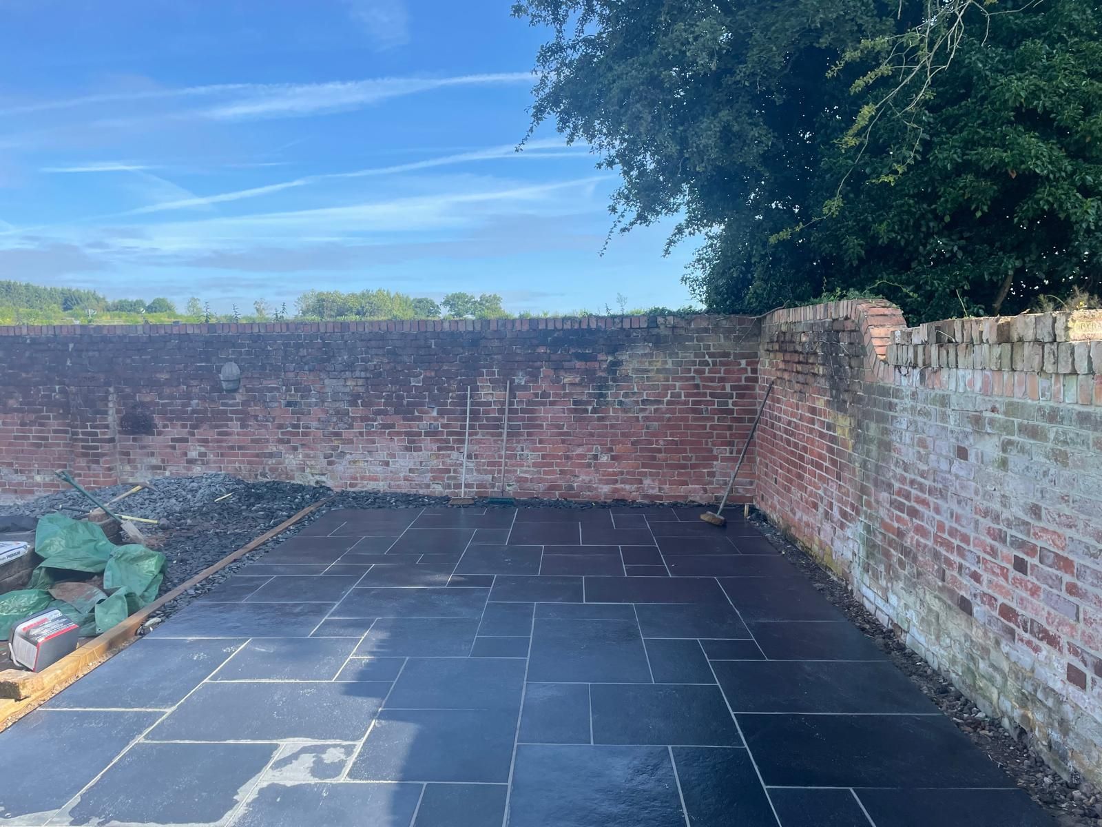 A brick wall with a black tile floor in front of it.