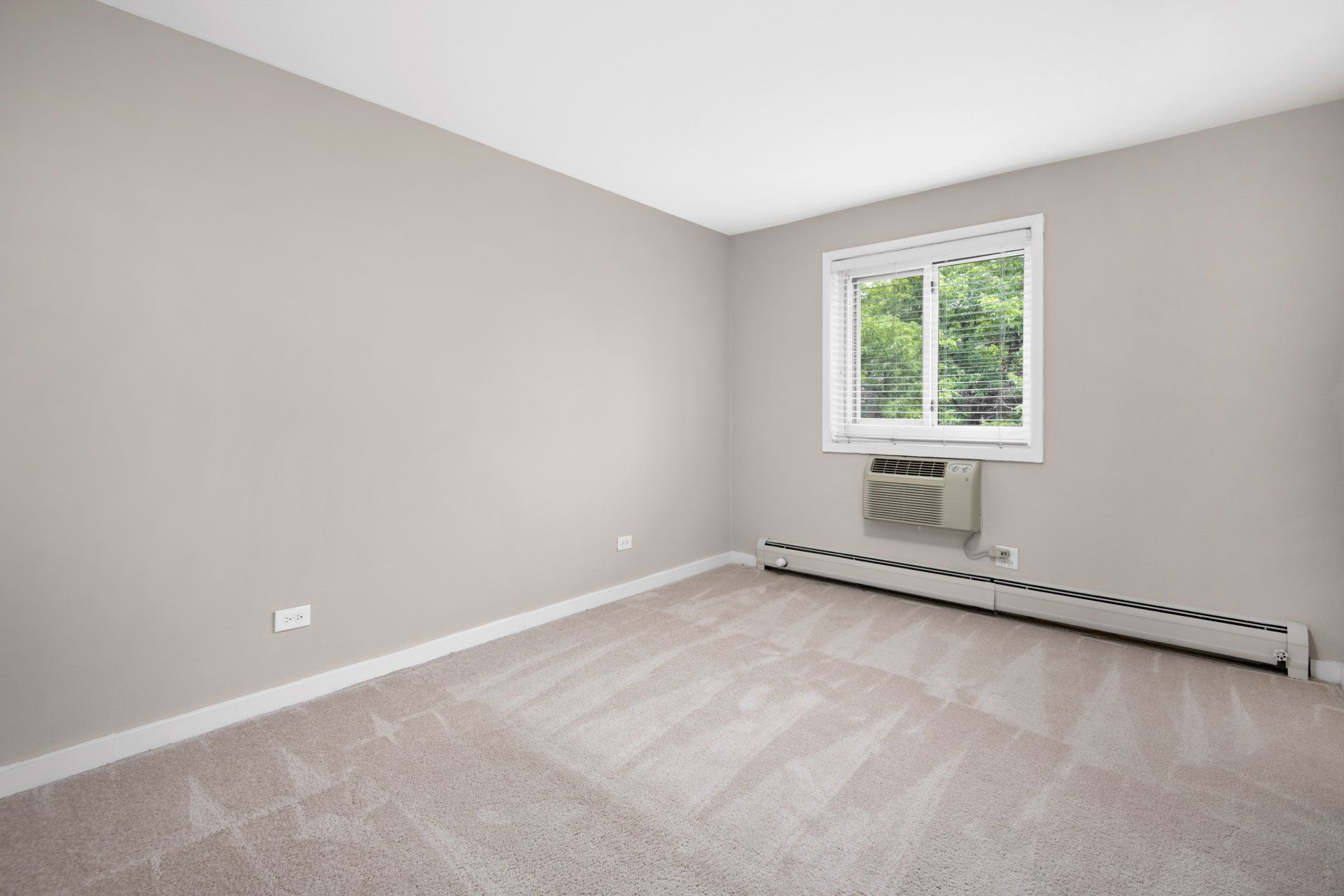 An empty bedroom with a window, carpet, and air conditioner at Reside 707.